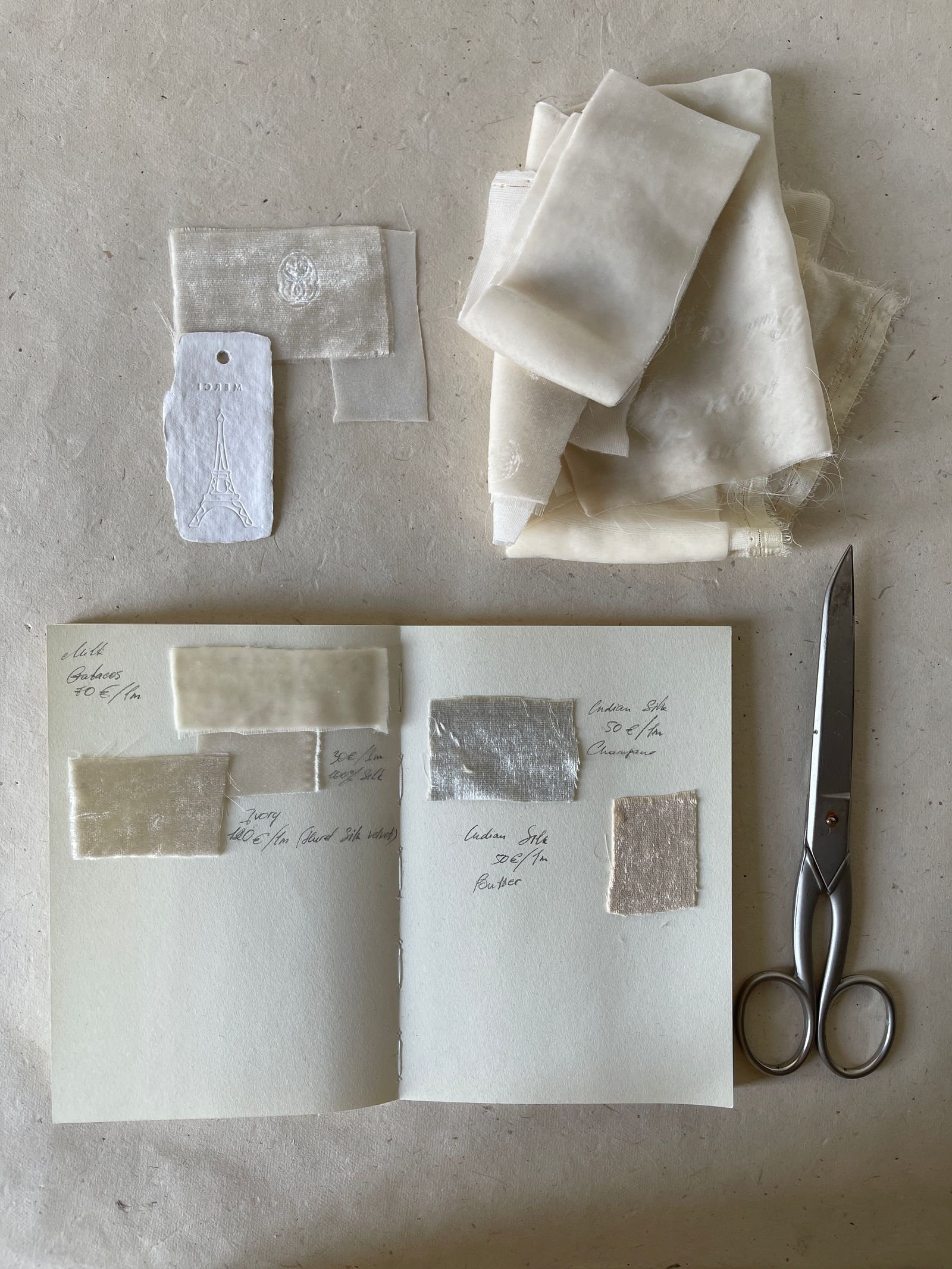 Scrapbook with fabric swatches, a paper tag, and scissors on a work table