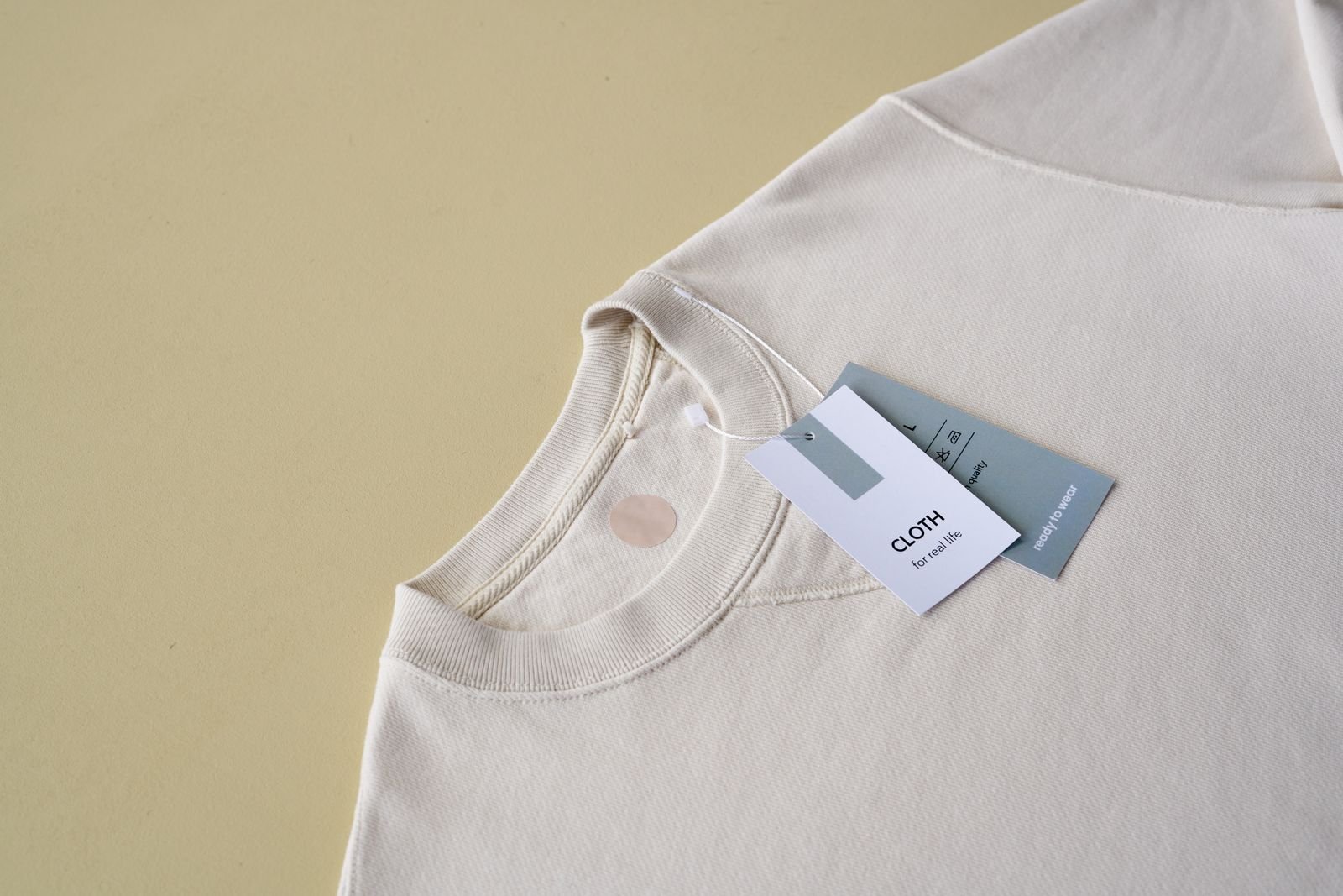 Beige sweatshirt laid out with printed clothing hang tags