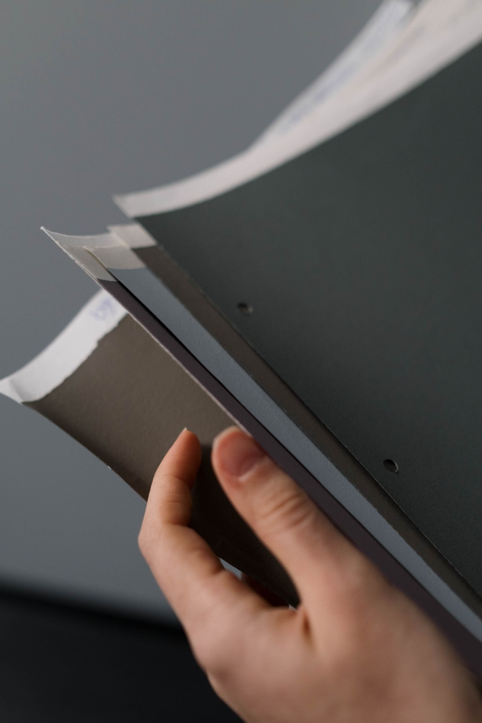 Een hand vergelijken fysieke papier monsters in verschillende texturen en kleuren