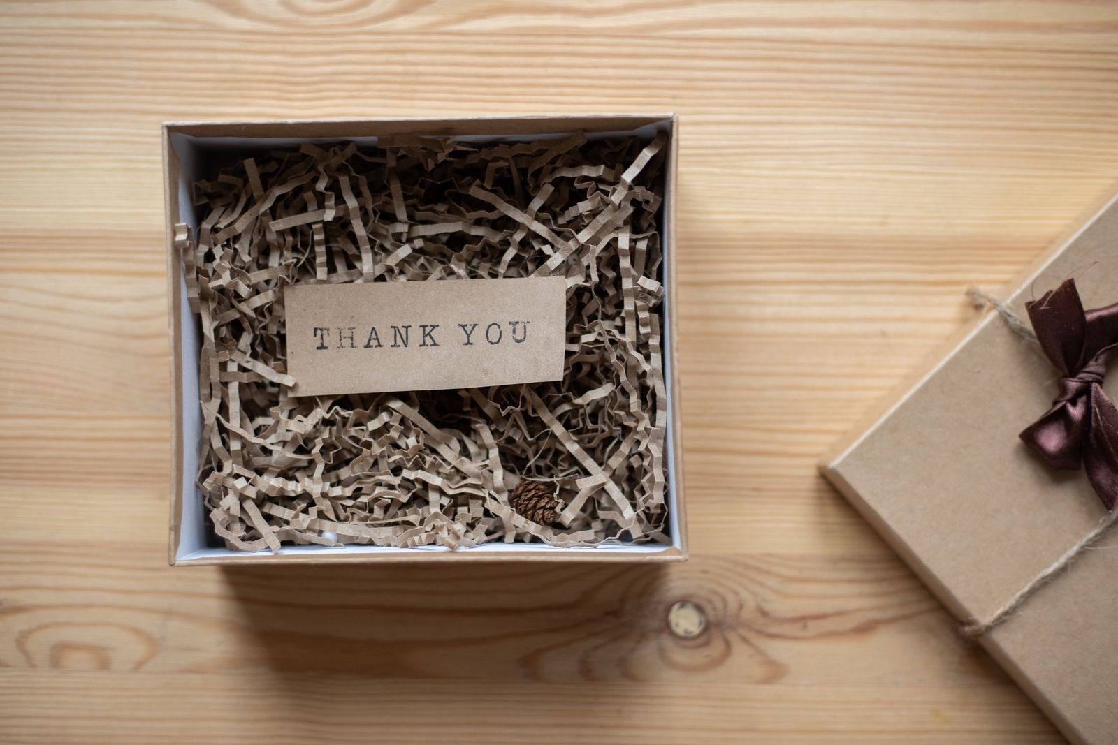 Offene Papp-Geschenkbox mit einer Dankeschön-Einsteckkarte und zerkleinertem Papier