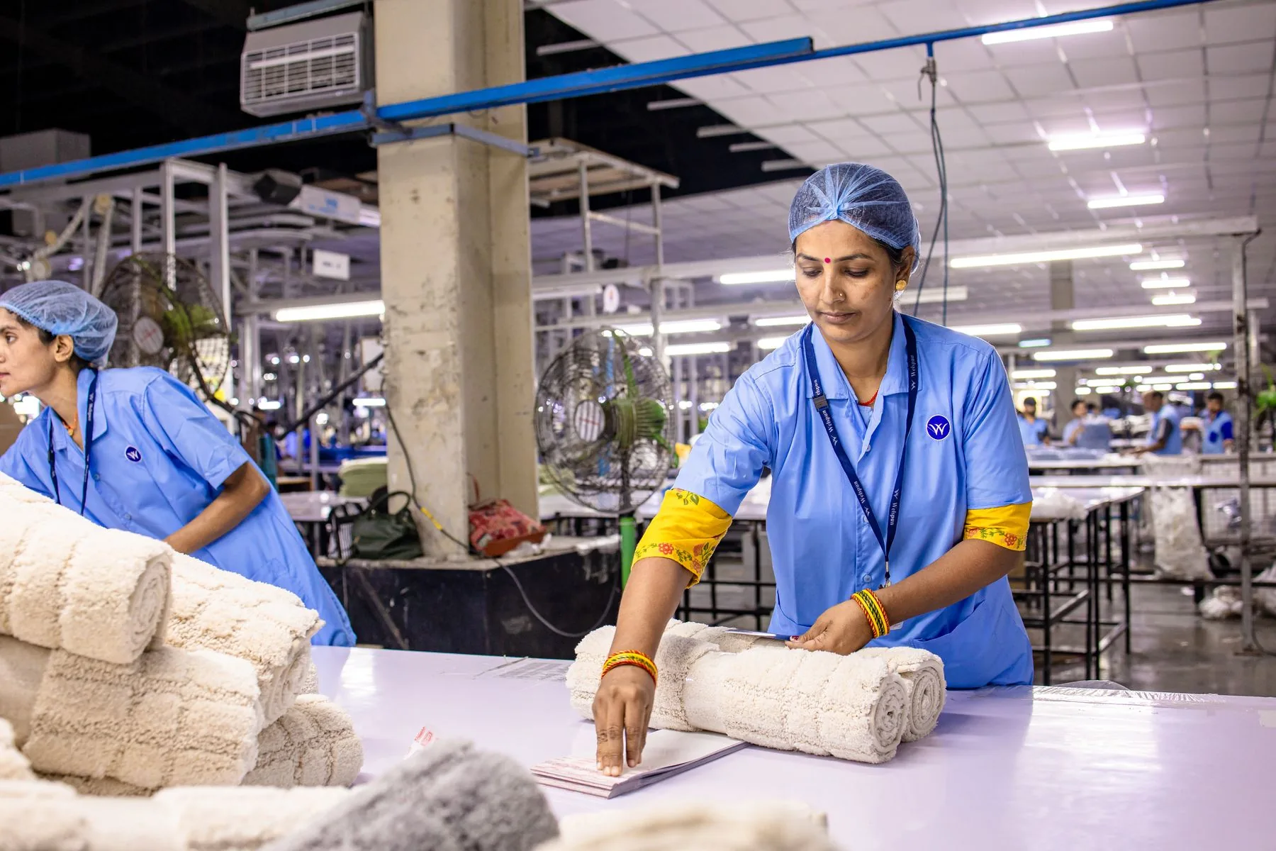 Textielfabriek werknemer het regelen van rollen van stof in een productie-installatie