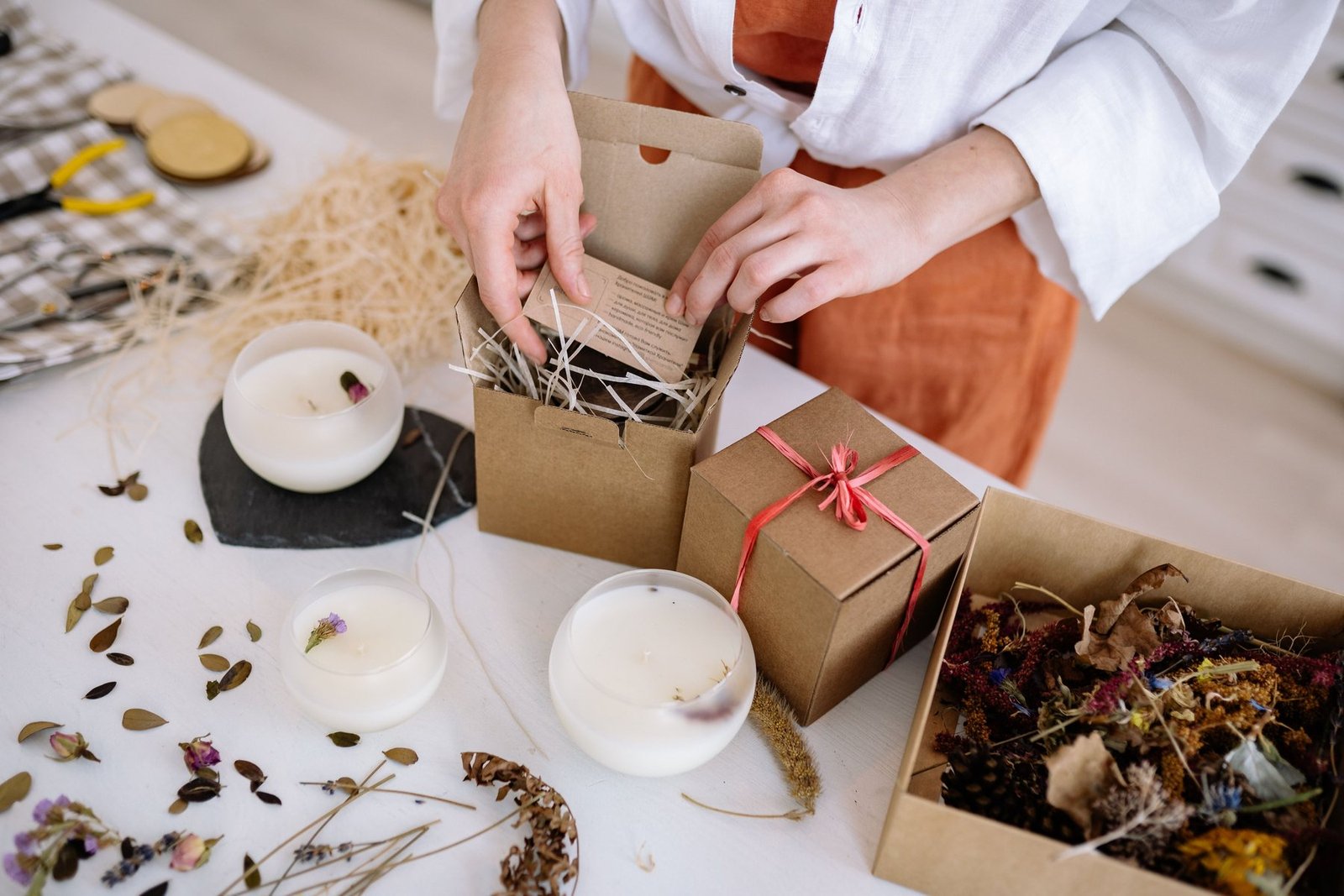 A person placing a printed card into a kraft paper product box during packing