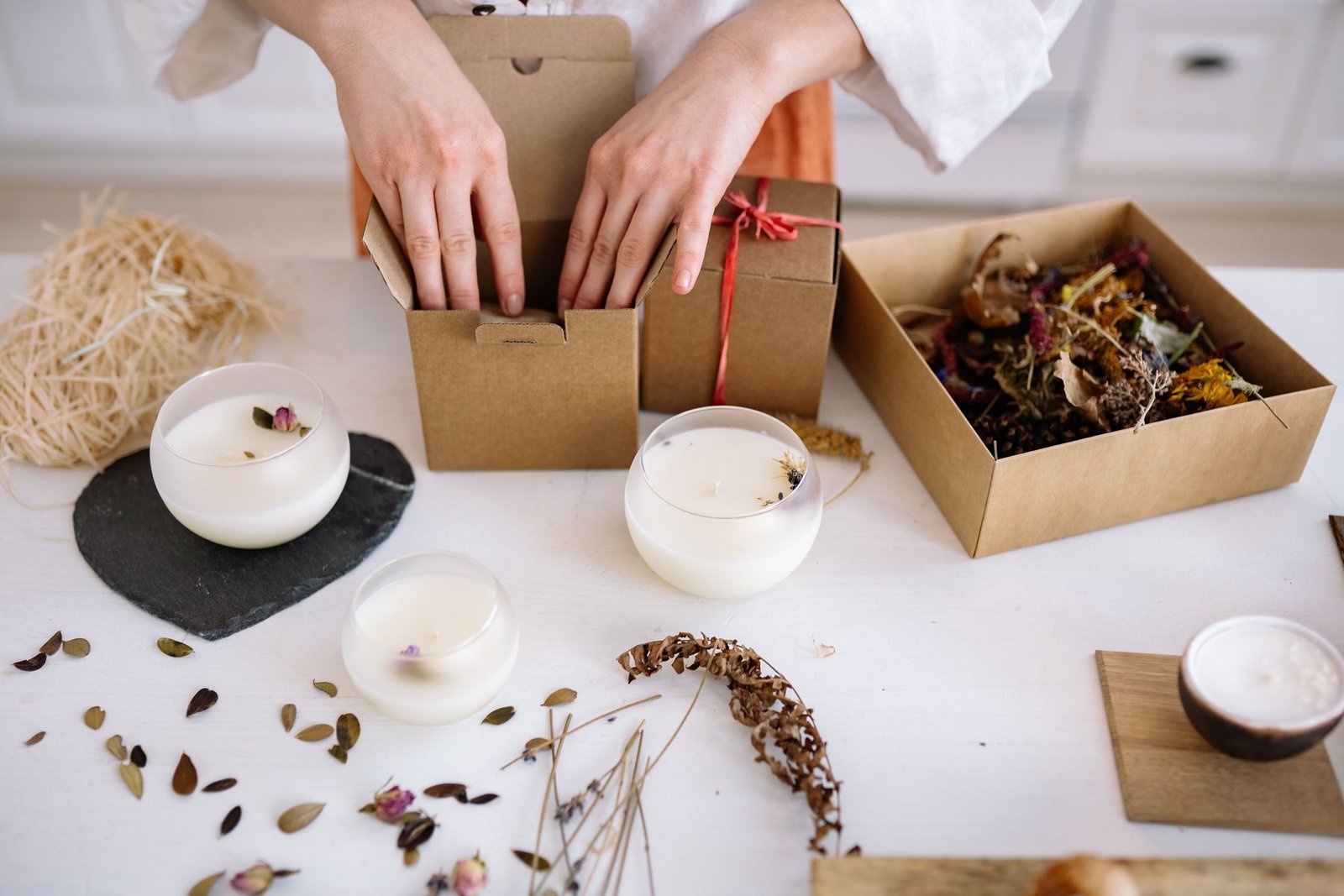 Bougies artisanales emballées avec des fleurs séchées dans des boîtes cadeaux en carton