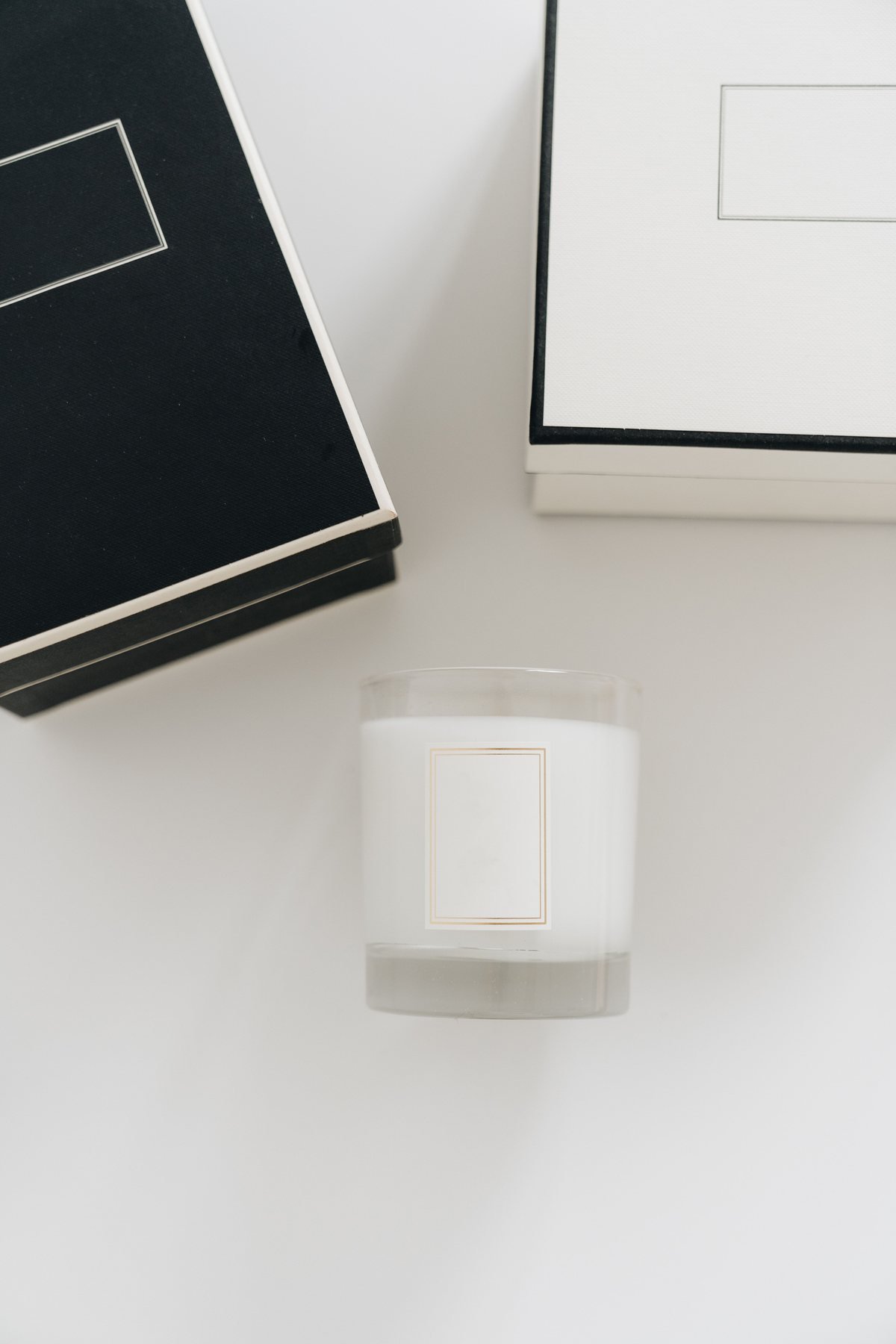 Bougie minimaliste affichée à côté des boîtes d'emballage noir et blanc