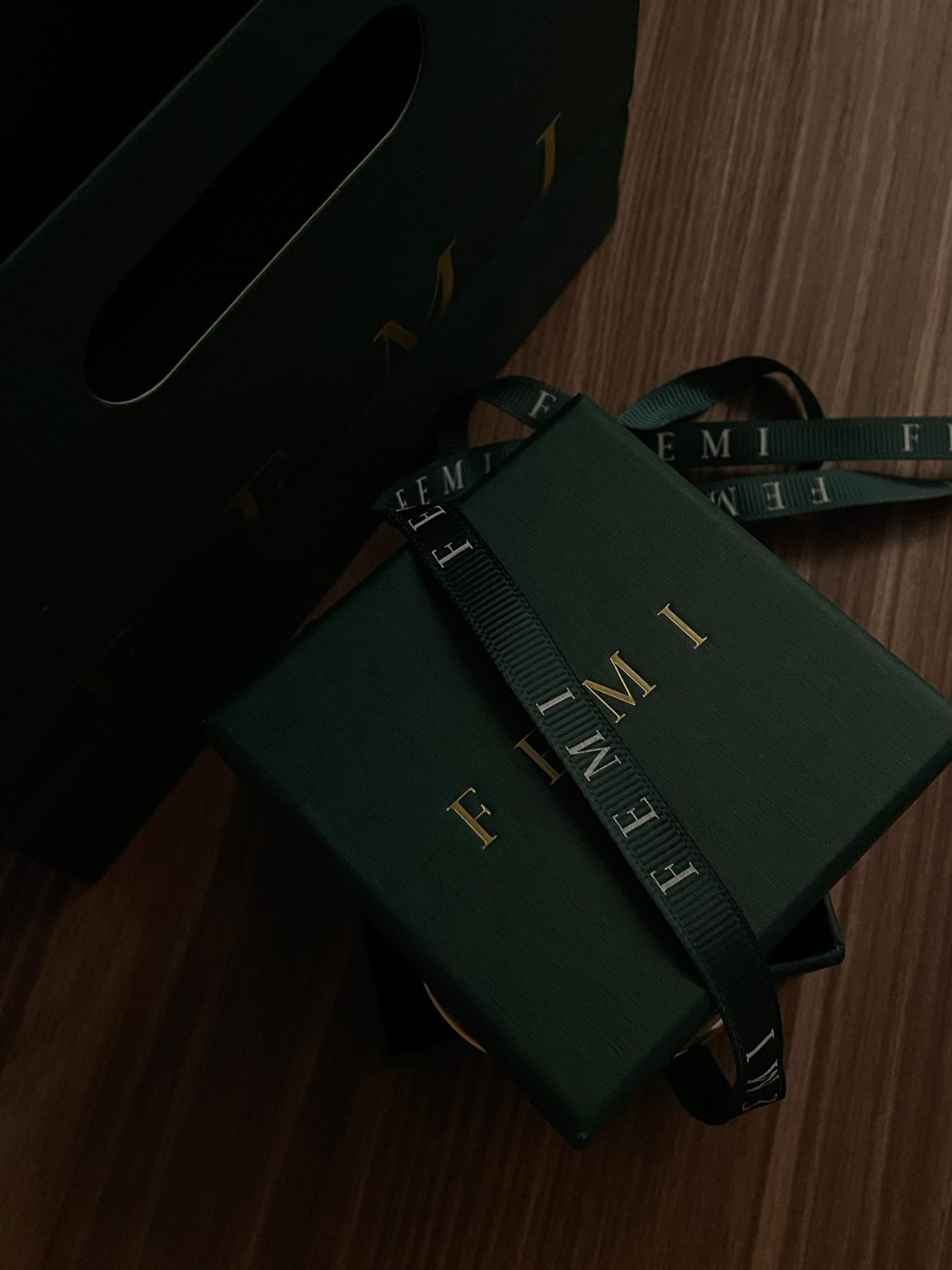 Dunkelgrüne Schmuck-Geschenkbox mit einem Band auf einer Holzoberfläche gebunden
