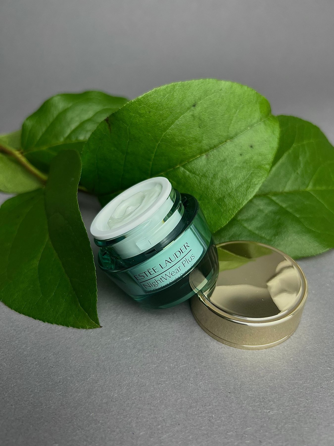 Skincare pot gestileerd met groene bladeren als referentie voor natuur-led schoonheid merkuitingen