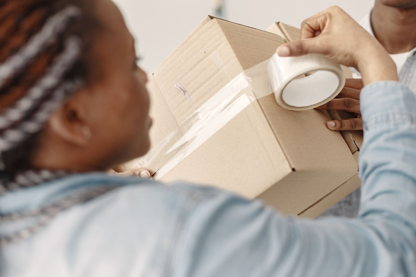 Nahaufnahme eines Packteams, das Klebeband auf eine Versandbox aufbringt