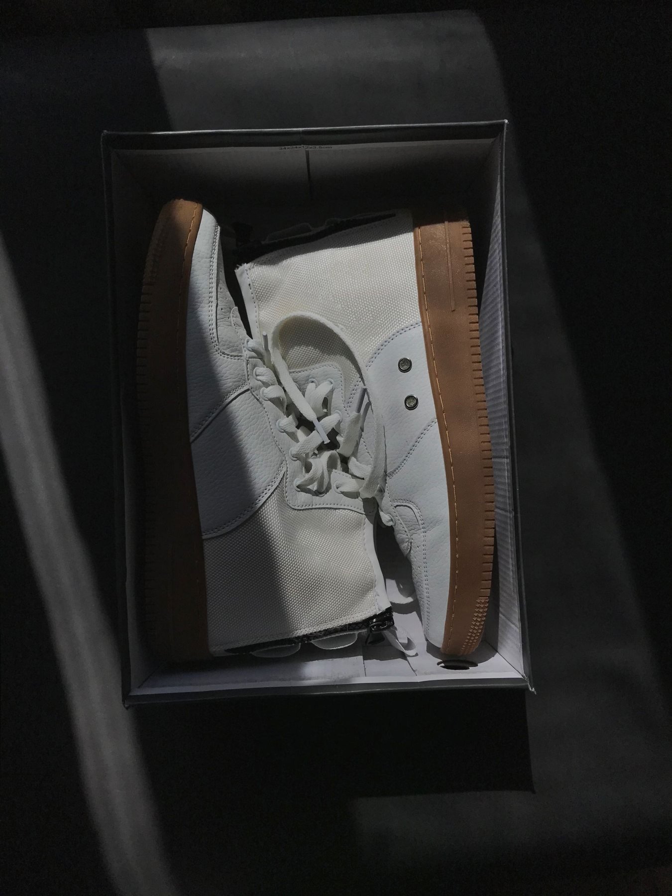 Weiße Sneaker in einem dunklen Schuhkarton zum Präsentationsvergleich