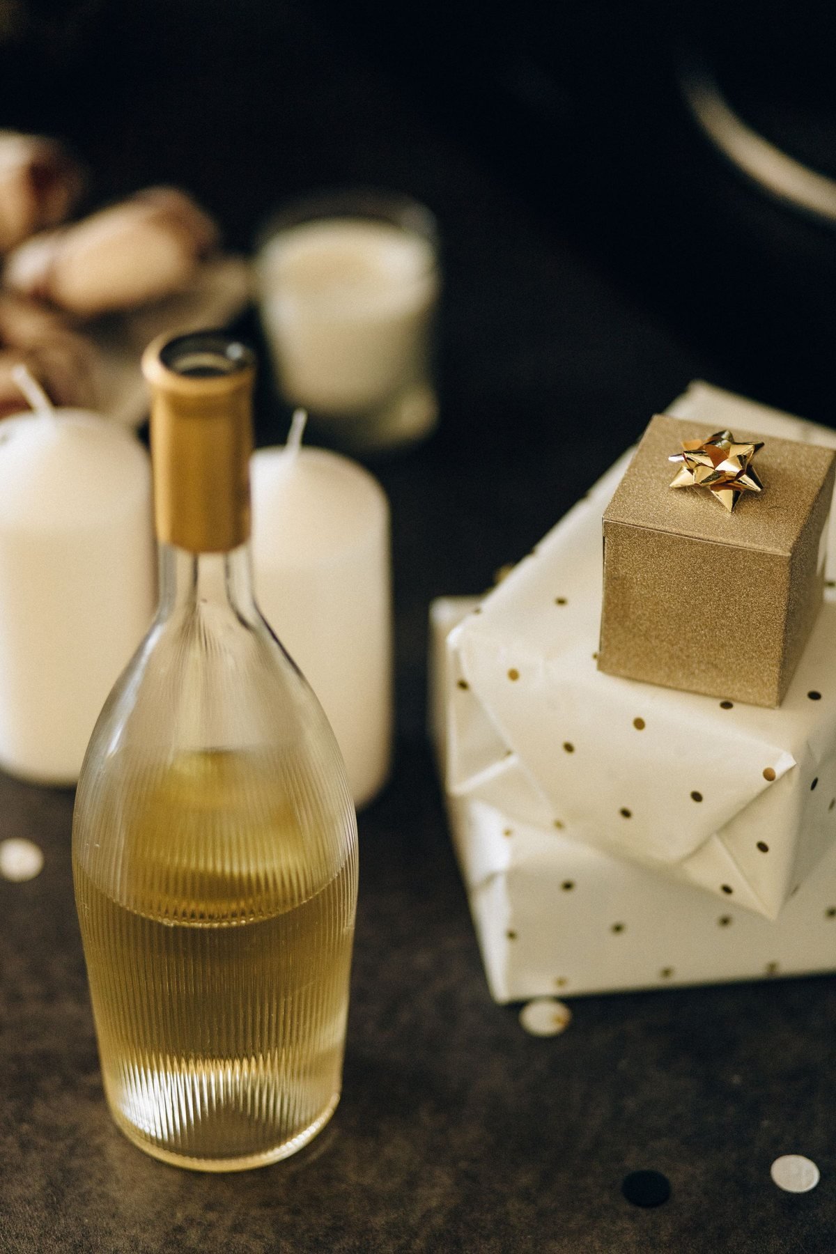 Eine Weinflasche neben eingewickelten Geschenken und Kerzen in einer Geschenkszene