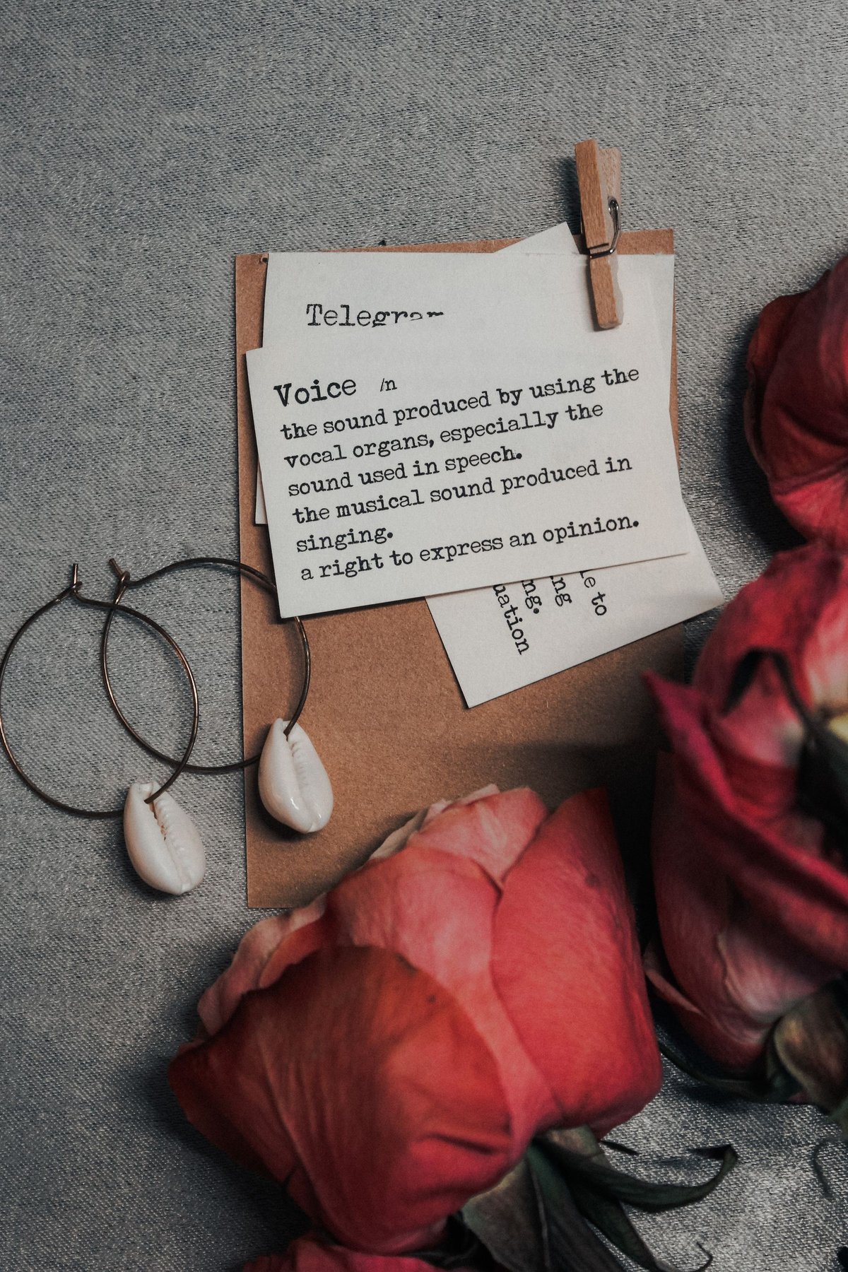 Dunkler Schmuck mit blassen Tropfendetails neben Papiernotizen und Rosen, mit Darstellung von Papier