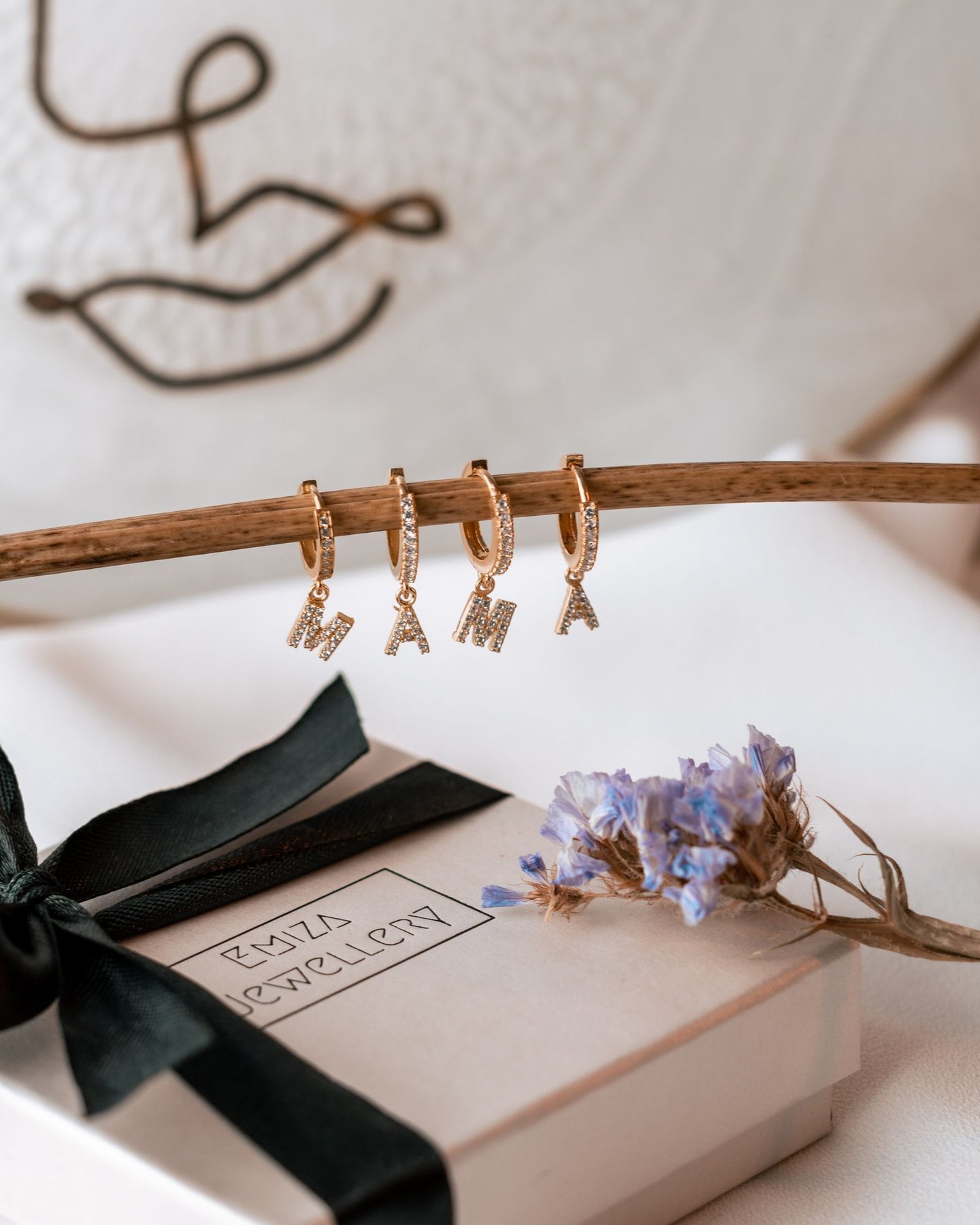 Kleine goldene Anfangsohrringe, die über einer Geschenkbox hängen und das Ausmaß des zarten Schmucks zeigen