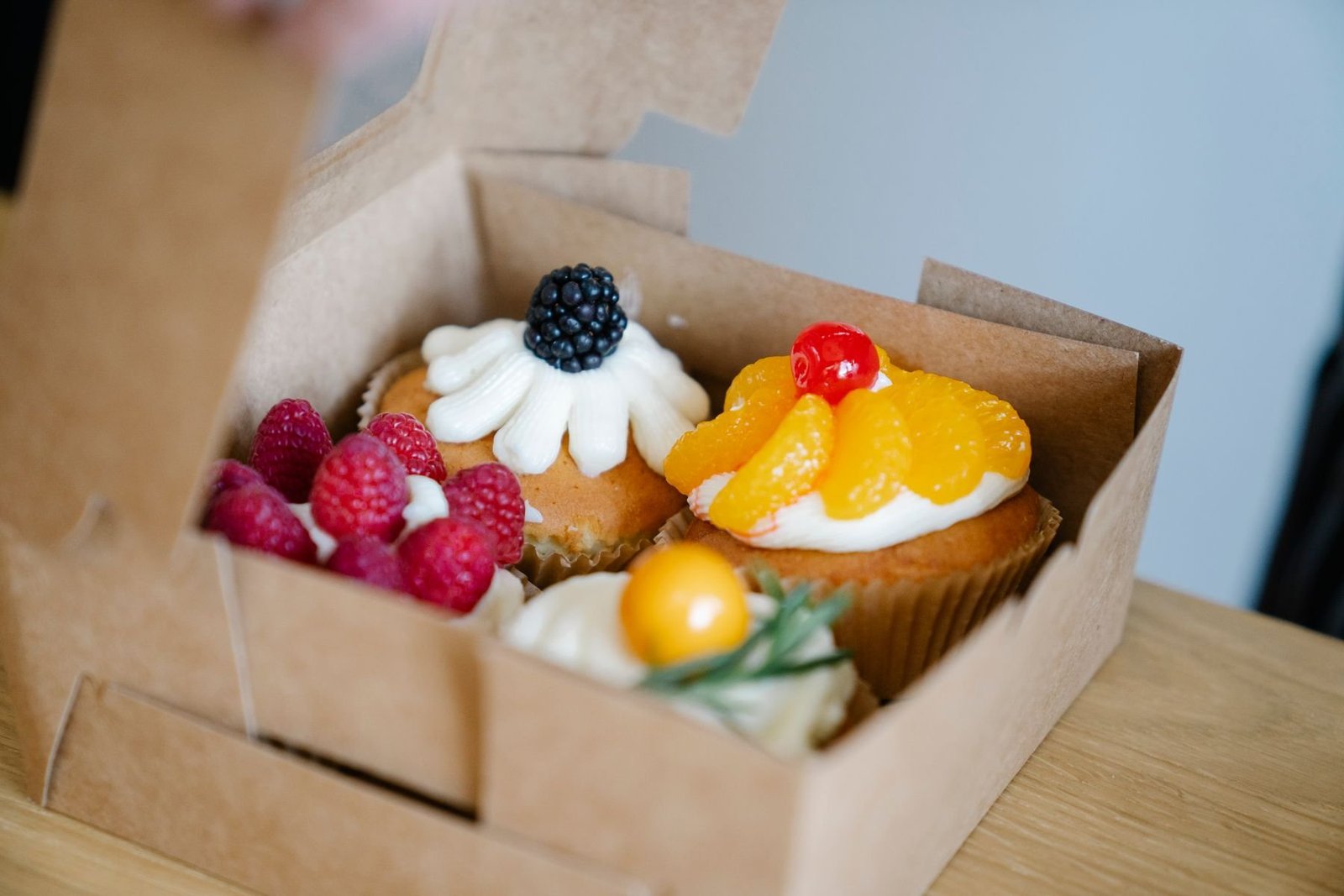 Fruit topped cupcakes inside a cardboard bakery box, showing why topping clearance matters
