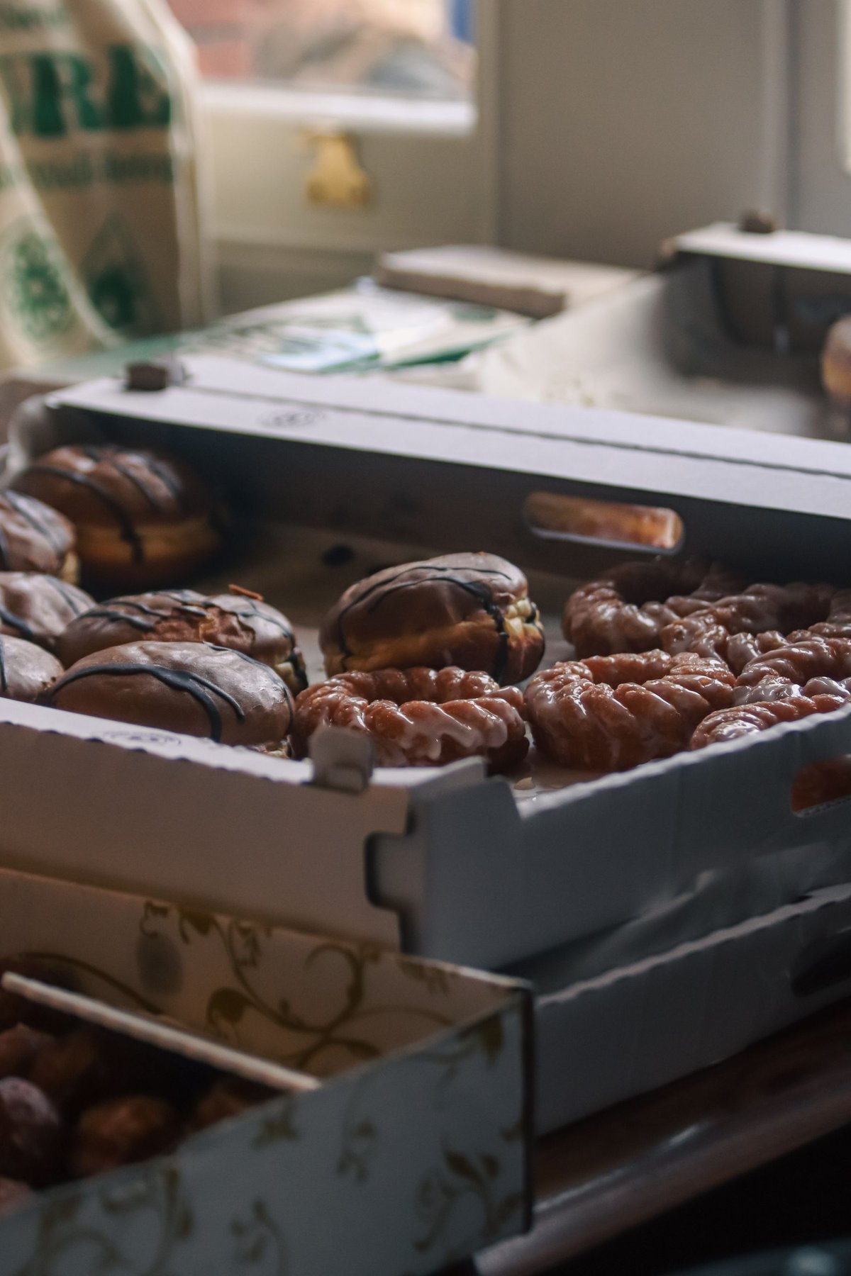 Sweet pastries packed in cardboard boxes beside a bakery window
