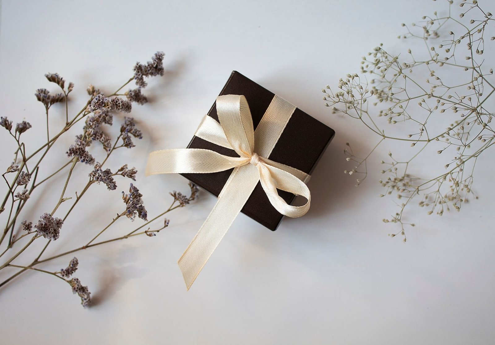 A black gift box with a pale ribbon and dried plants, illustrating details vulnerable to handling marks