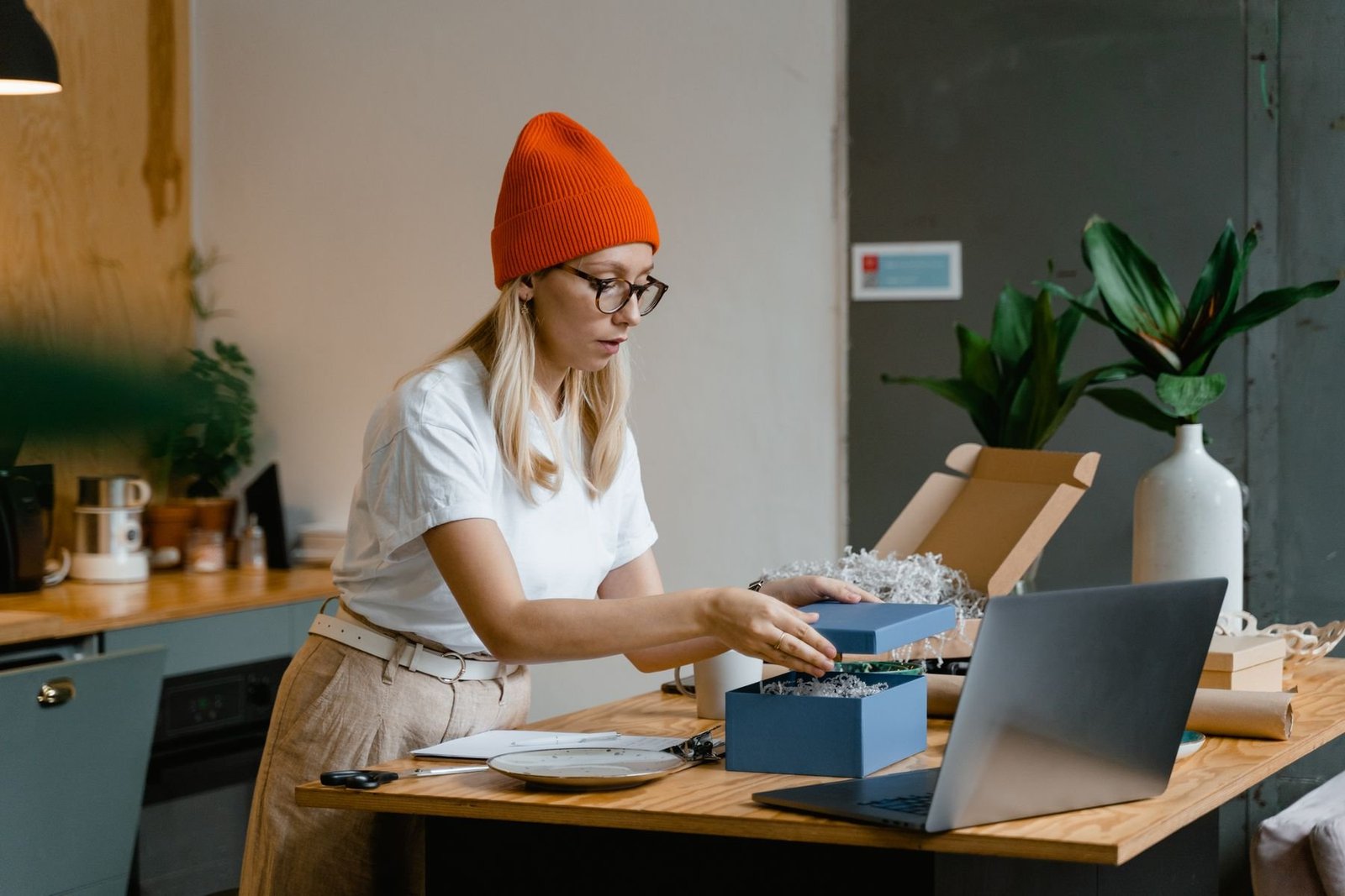 A woman holding a separate blue box lid while preparing a presentation package