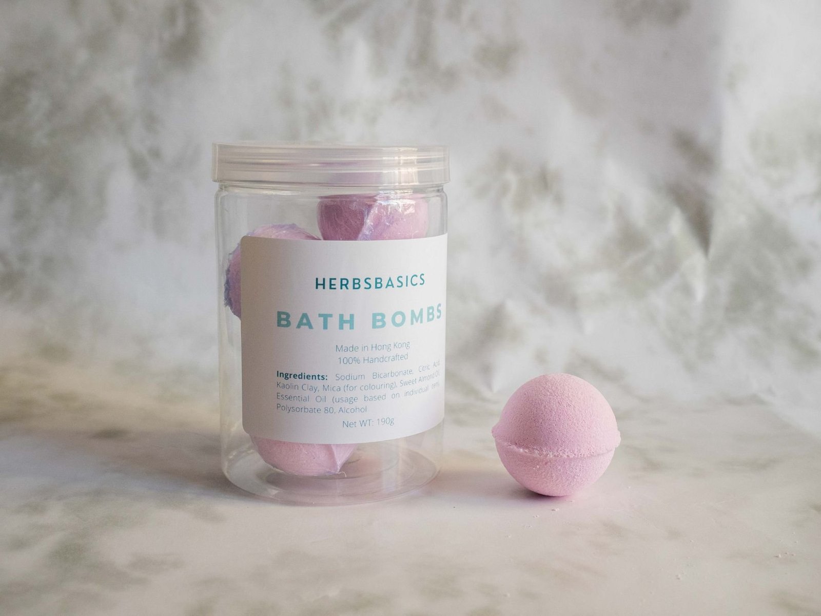 Pink bath bombs displayed inside a clear labeled container