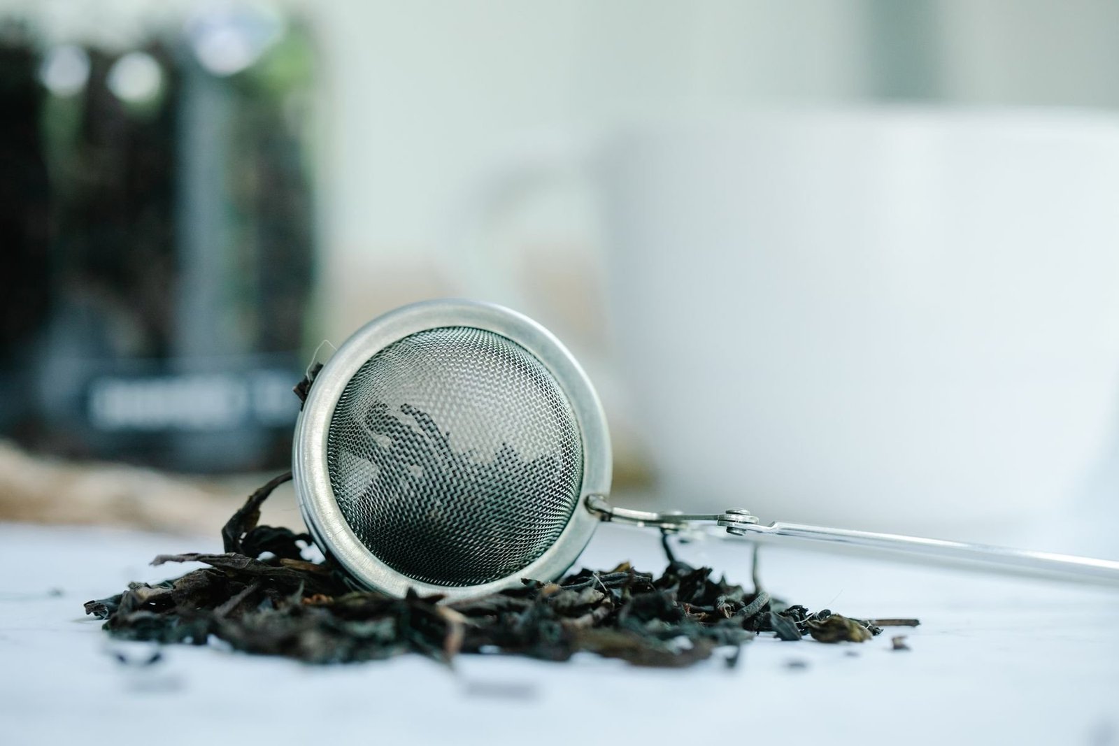 Loose tea leaves arranged beside a metal tea infuser