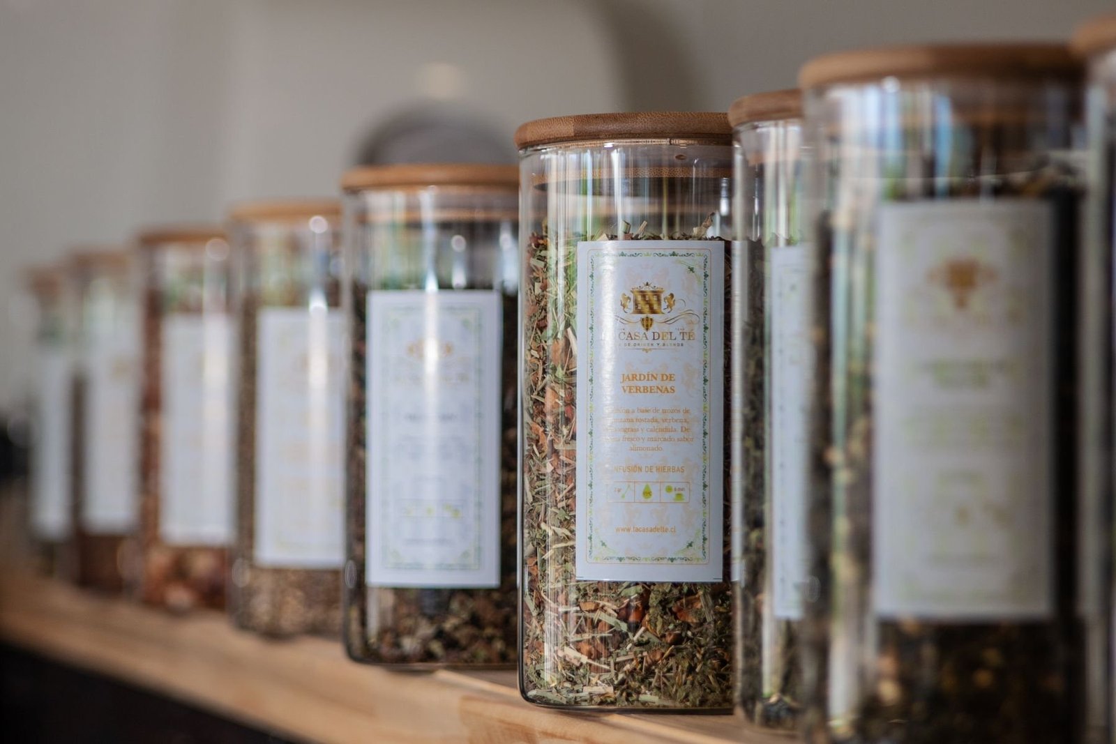 Several tea varieties displayed in labeled glass jars with wooden lids