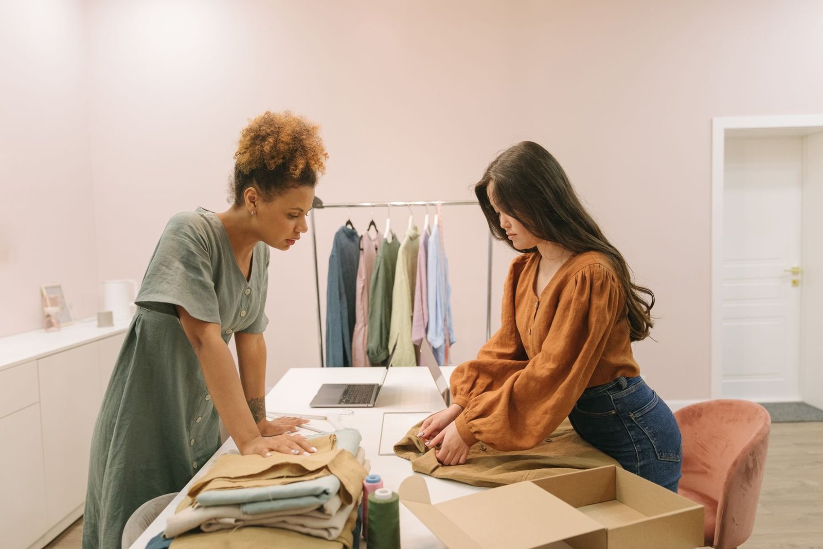 Two clothing business owners folding garments and preparing an order at a worktable