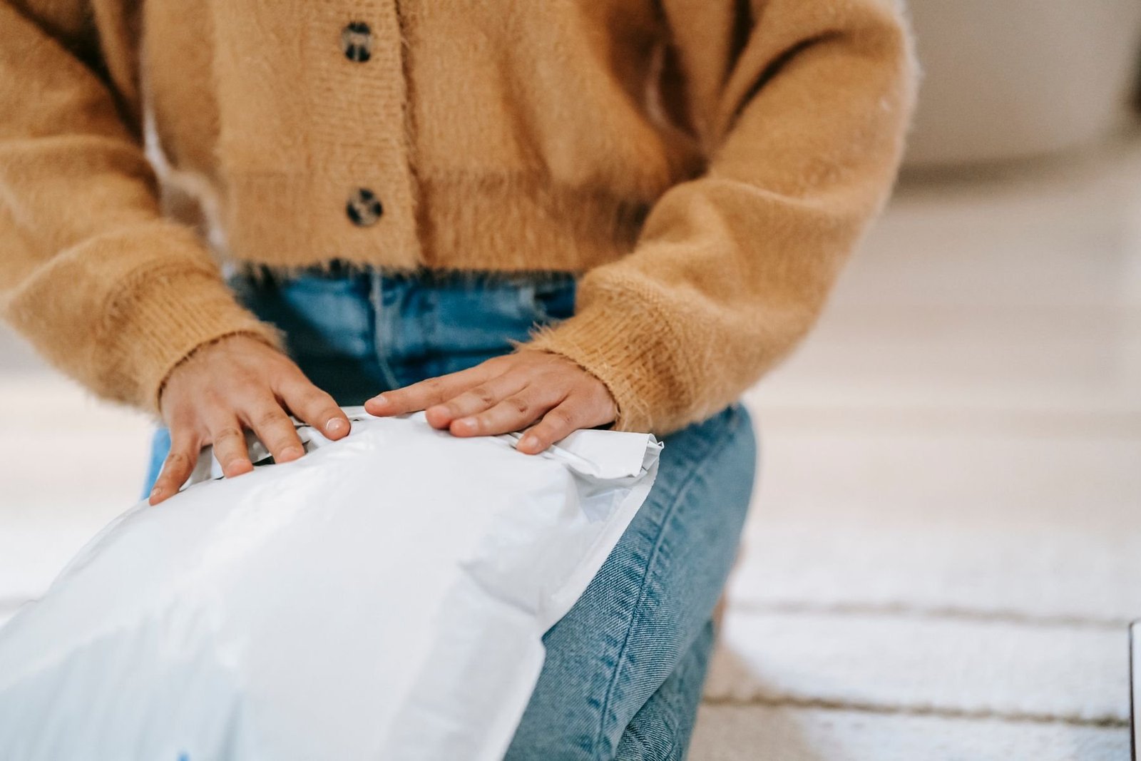 A customer opening a white flexible parcel mailer indoors