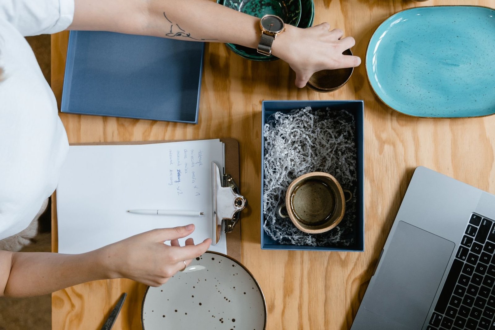 Overhead view of a ceramic seller preparing a mug order with a box and packing materials