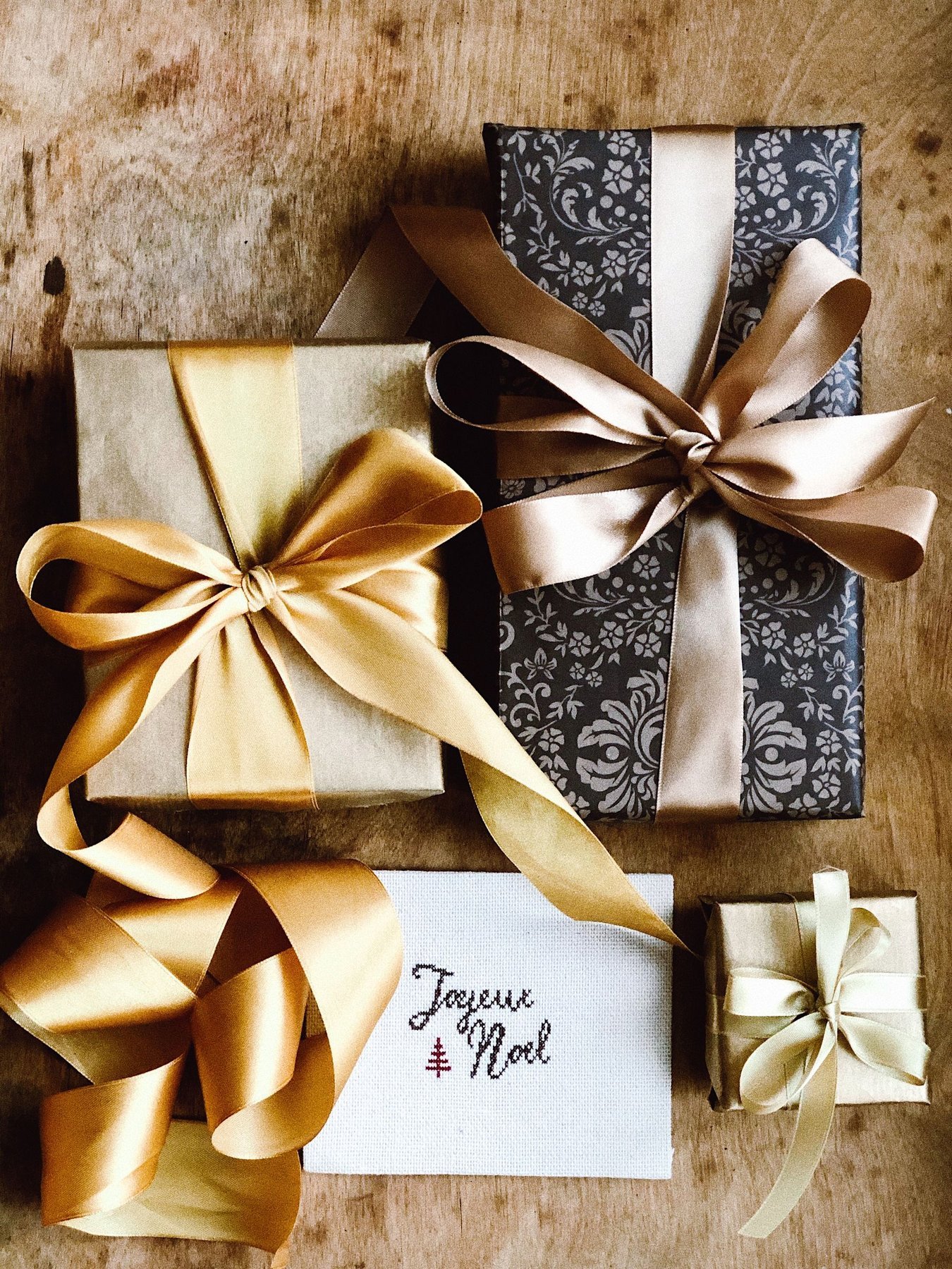 Wrapped gifts with satin ribbons and a Joyeux Noel message card