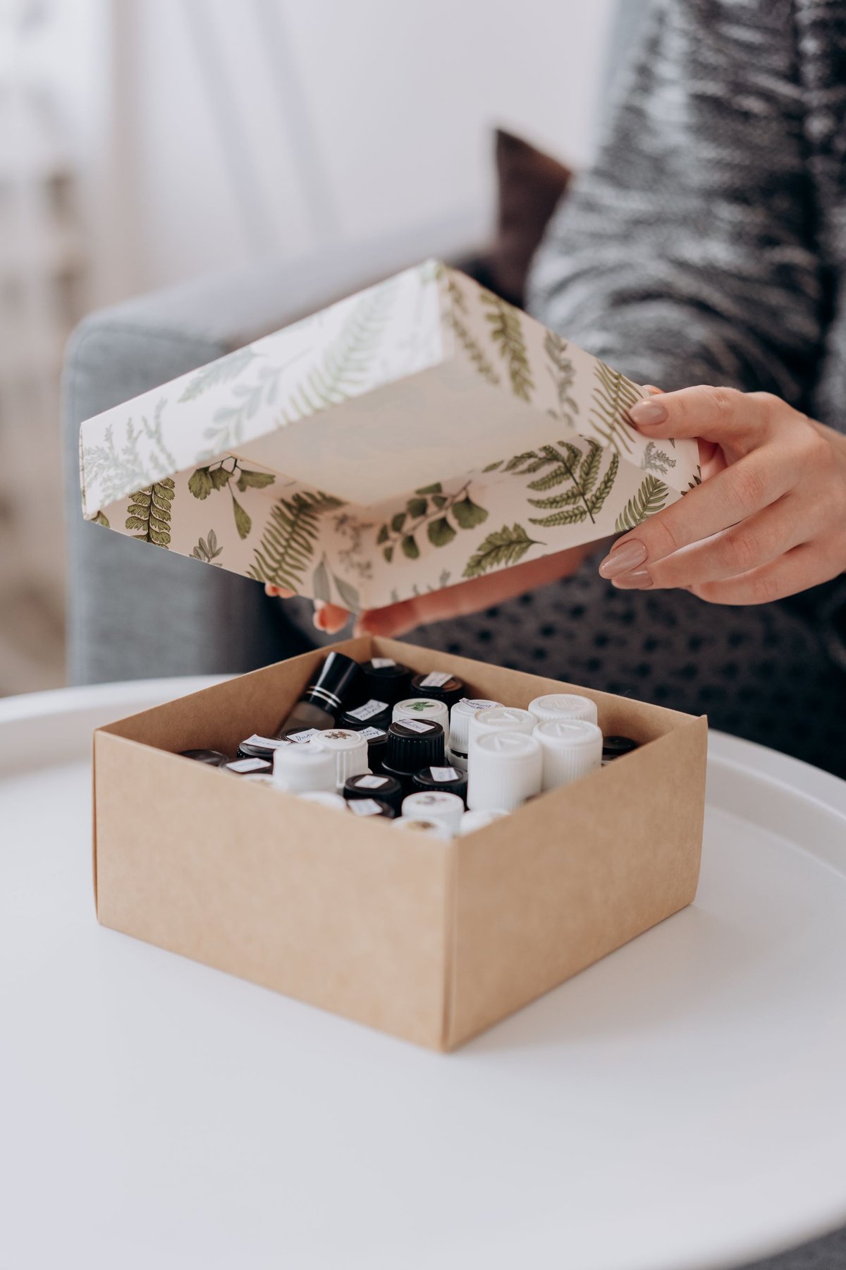 A person lifting the lid from a box holding small essential oil bottles