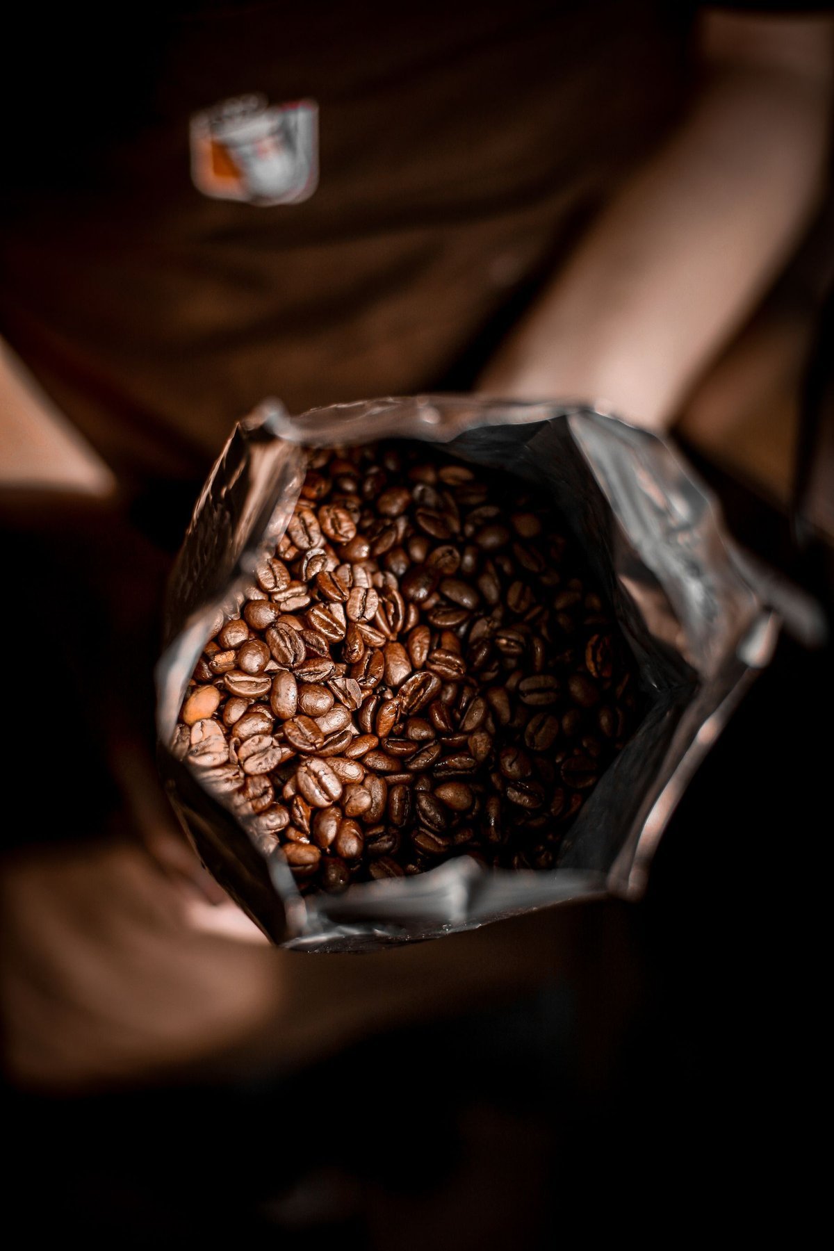 A barista holding an open package filled with roasted coffee beans