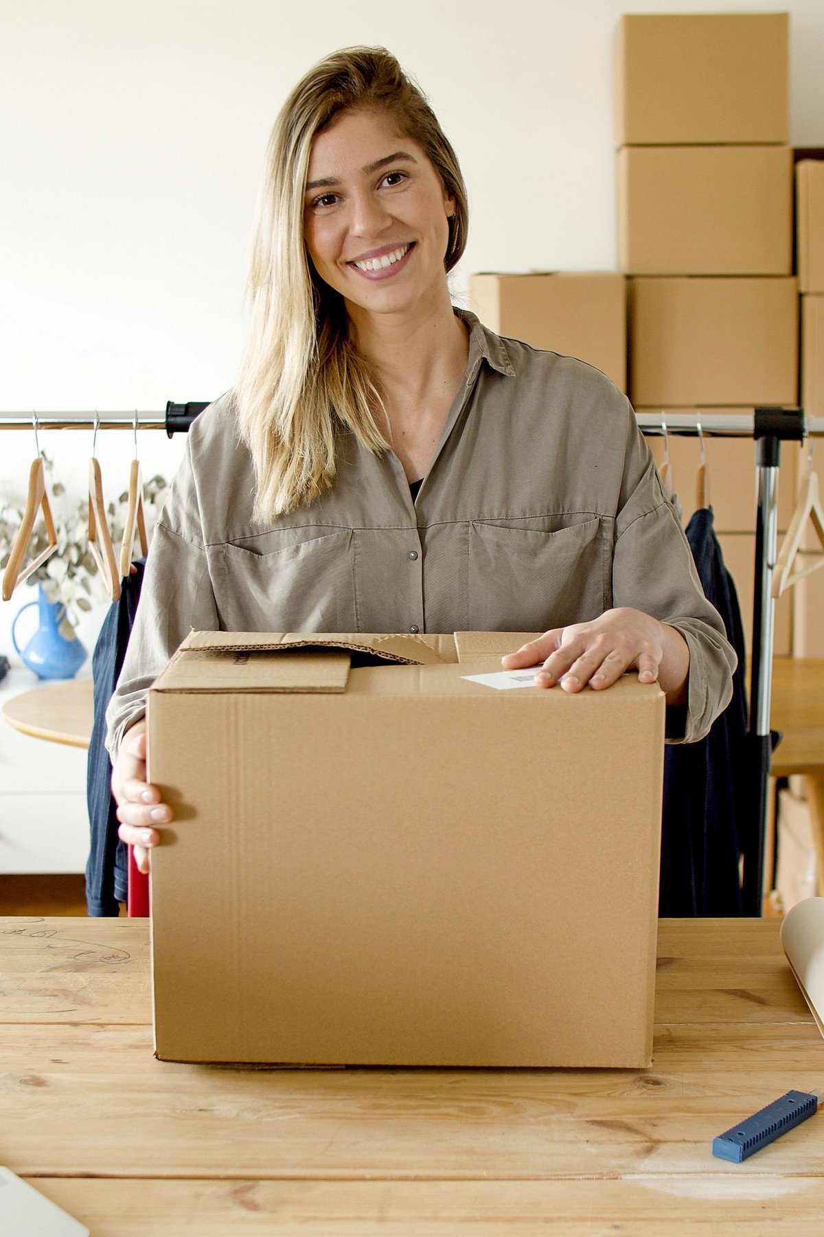 A small business owner holding a box at a packing table