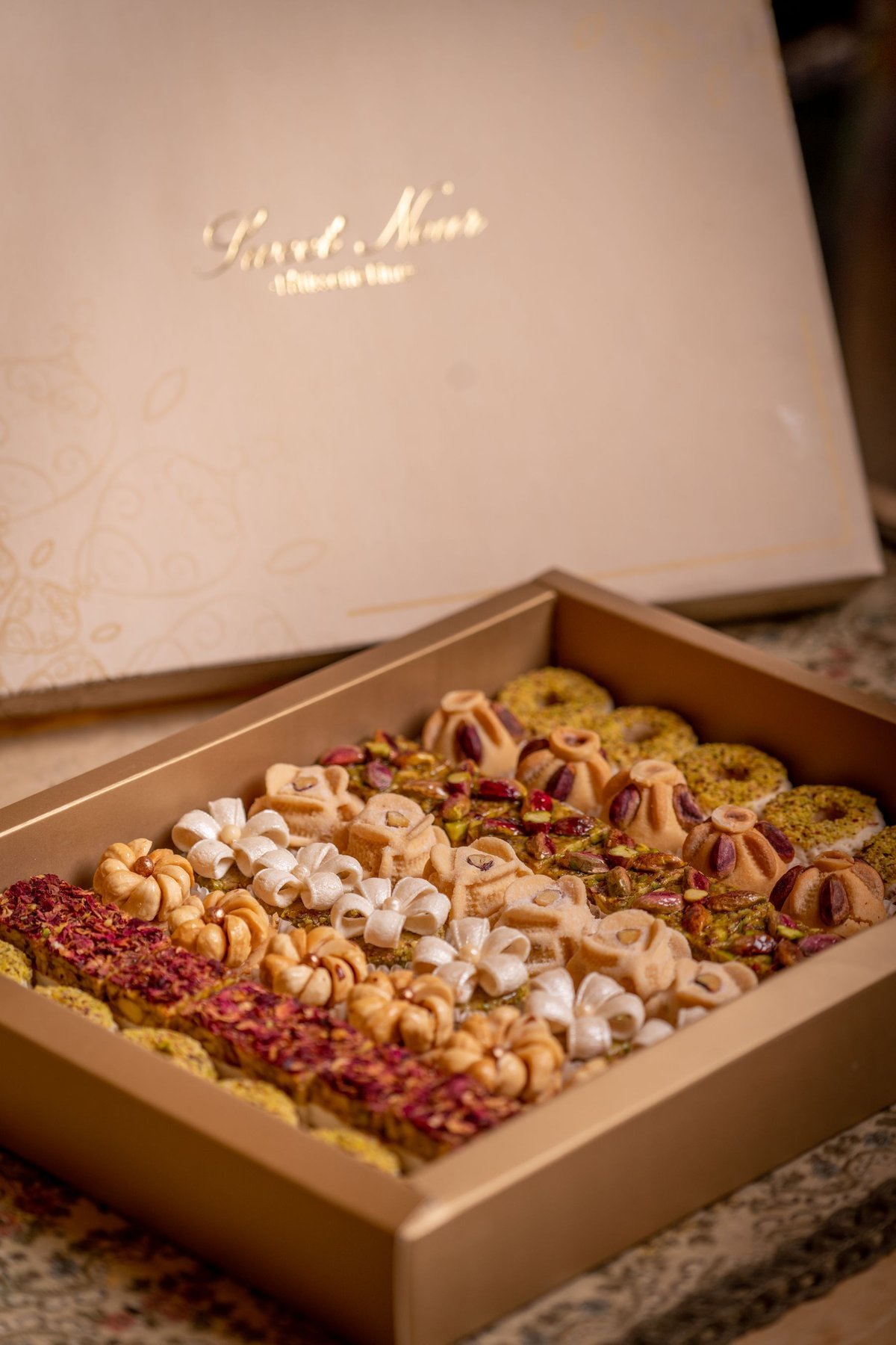 An open gift box with individually arranged cookies and sweets
