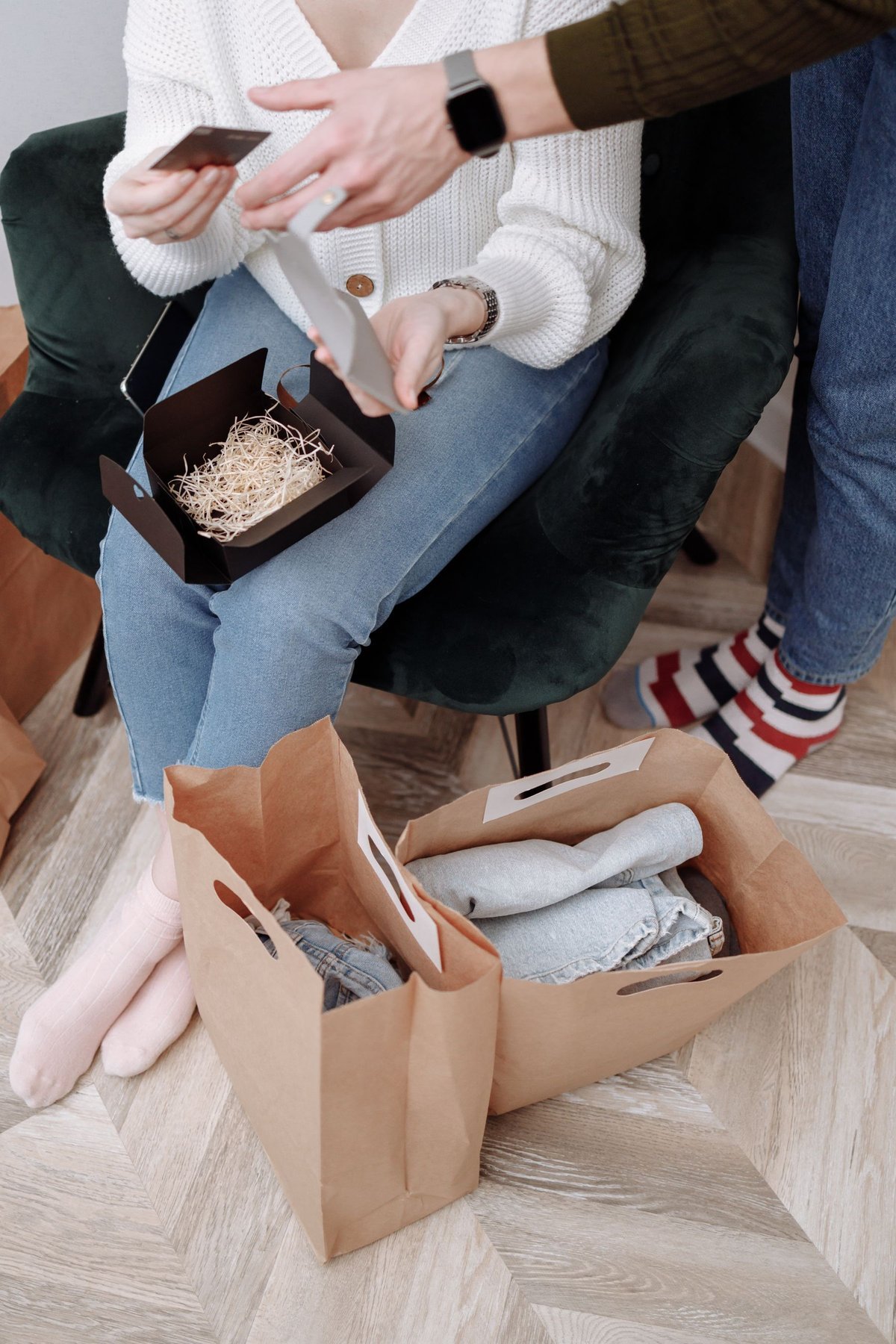 People unpacking gifts beside filled paper bags on a wooden floor
