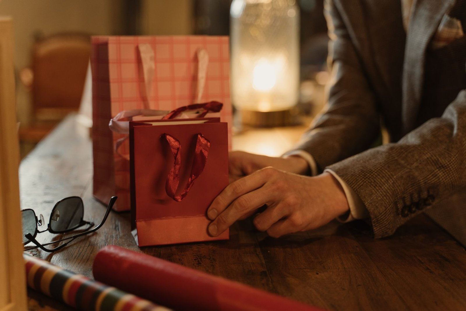Hands arranging paper gift bags on a wooden table