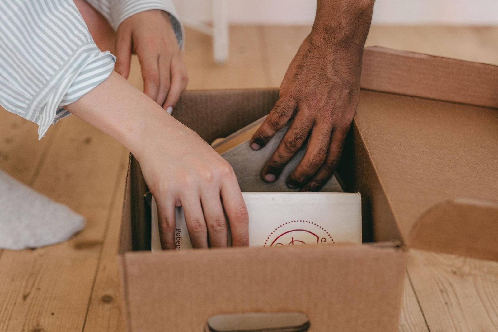 Hands organizing books inside a cardboard box