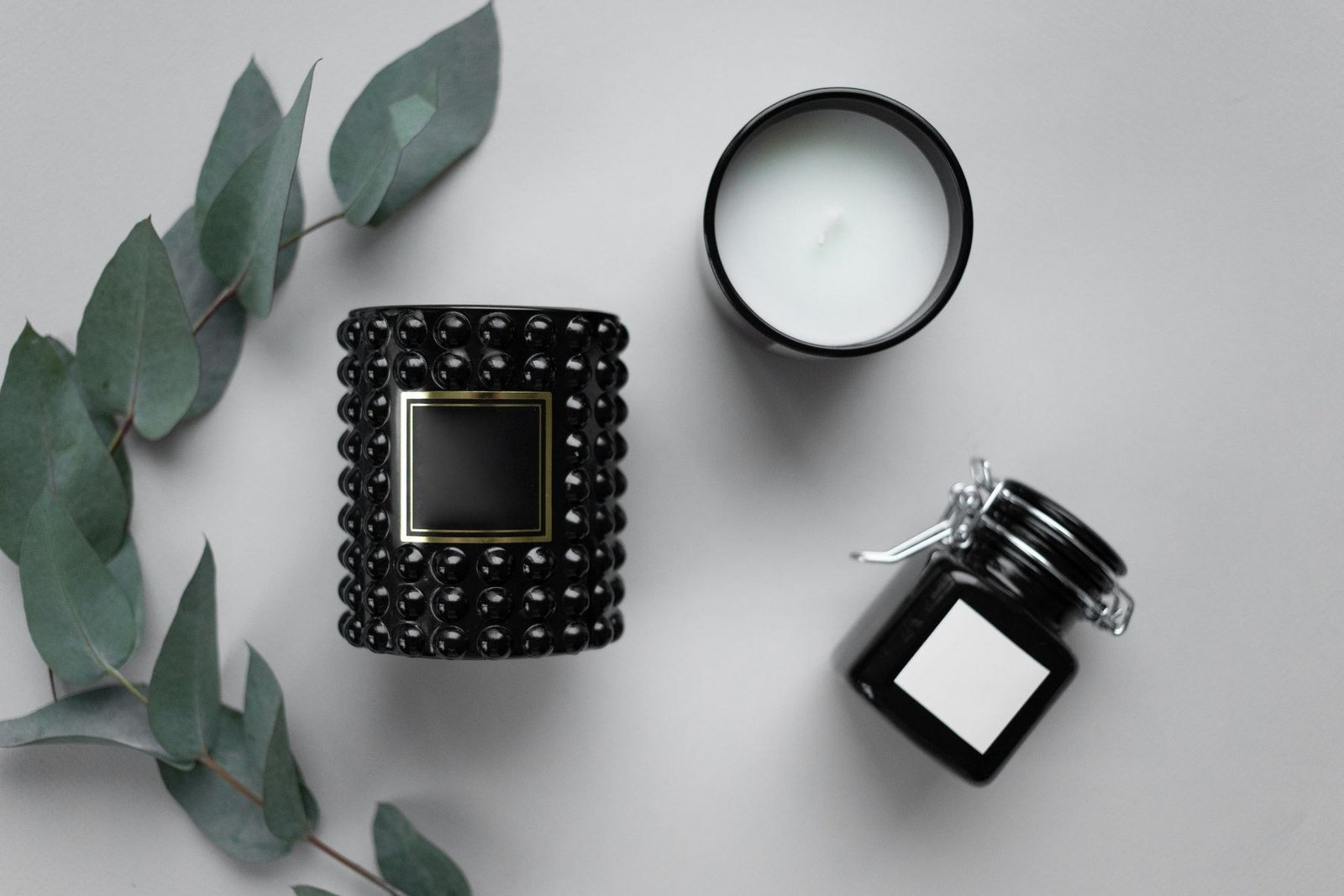 Black decorative containers with contrasting label areas on a gray surface