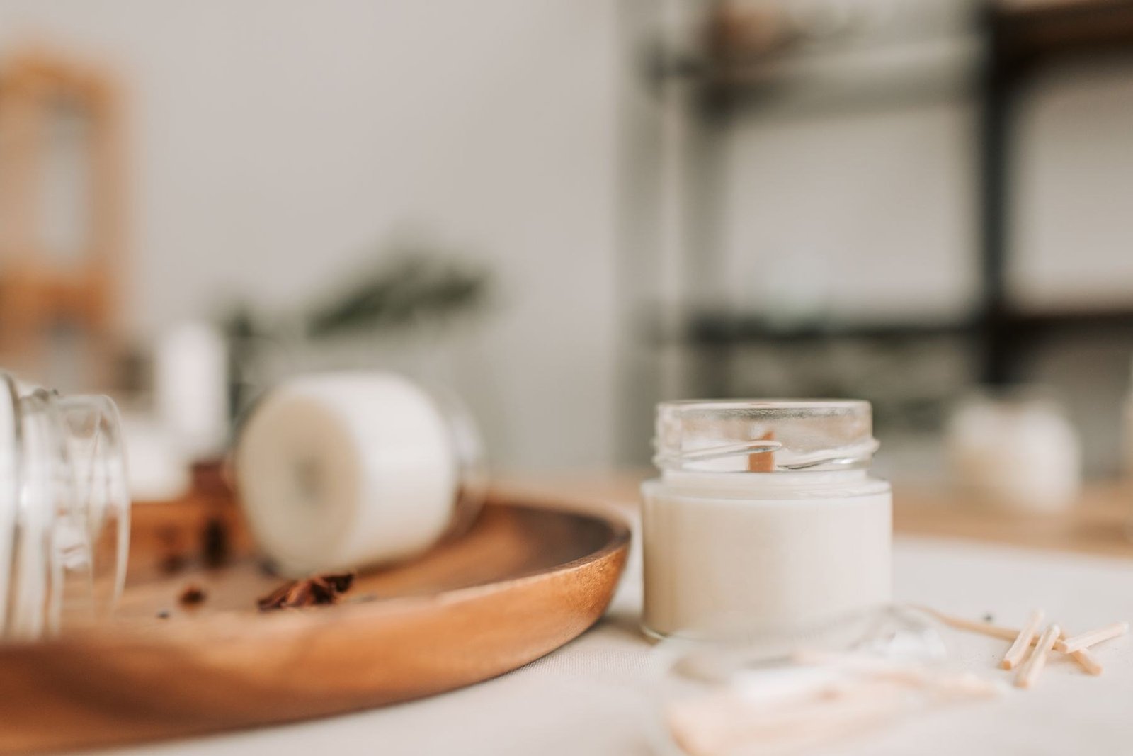 A clear glass candle jar sitting on a wooden tray