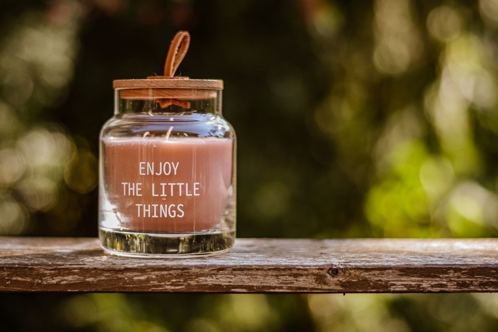A glass candle jar with the short message Enjoy the Little Things