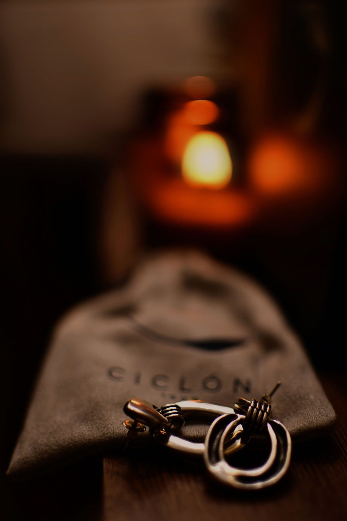 Earrings resting beside the gathered closure of a fabric jewelry bag