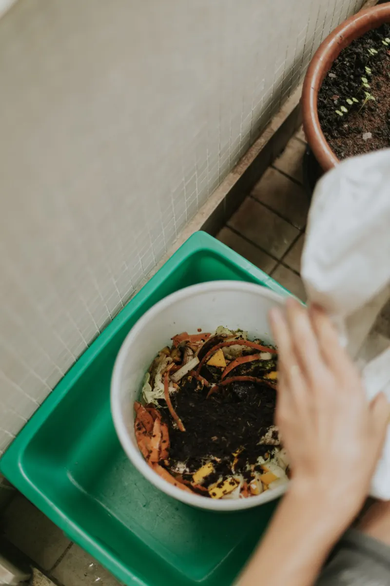 Hands adding food scraps to a compost container