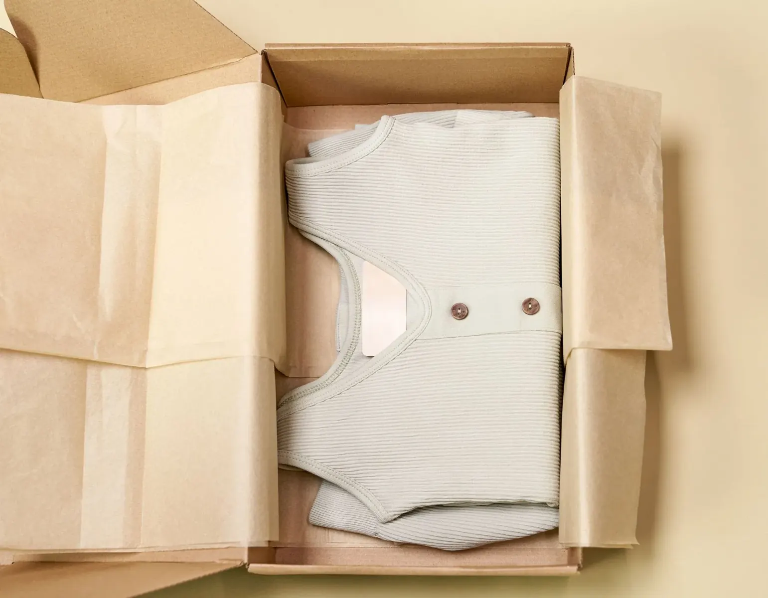 Folded knitwear packed in a cardboard fashion box with tissue paper