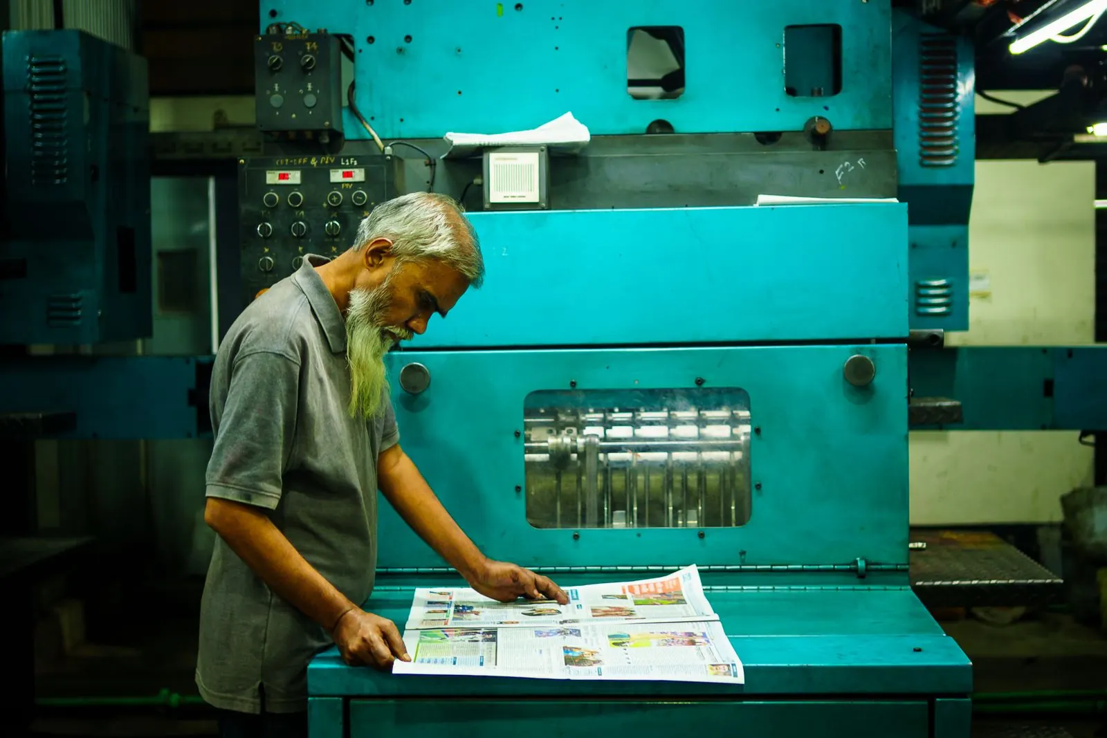 A print operator reviewing freshly printed sheets
