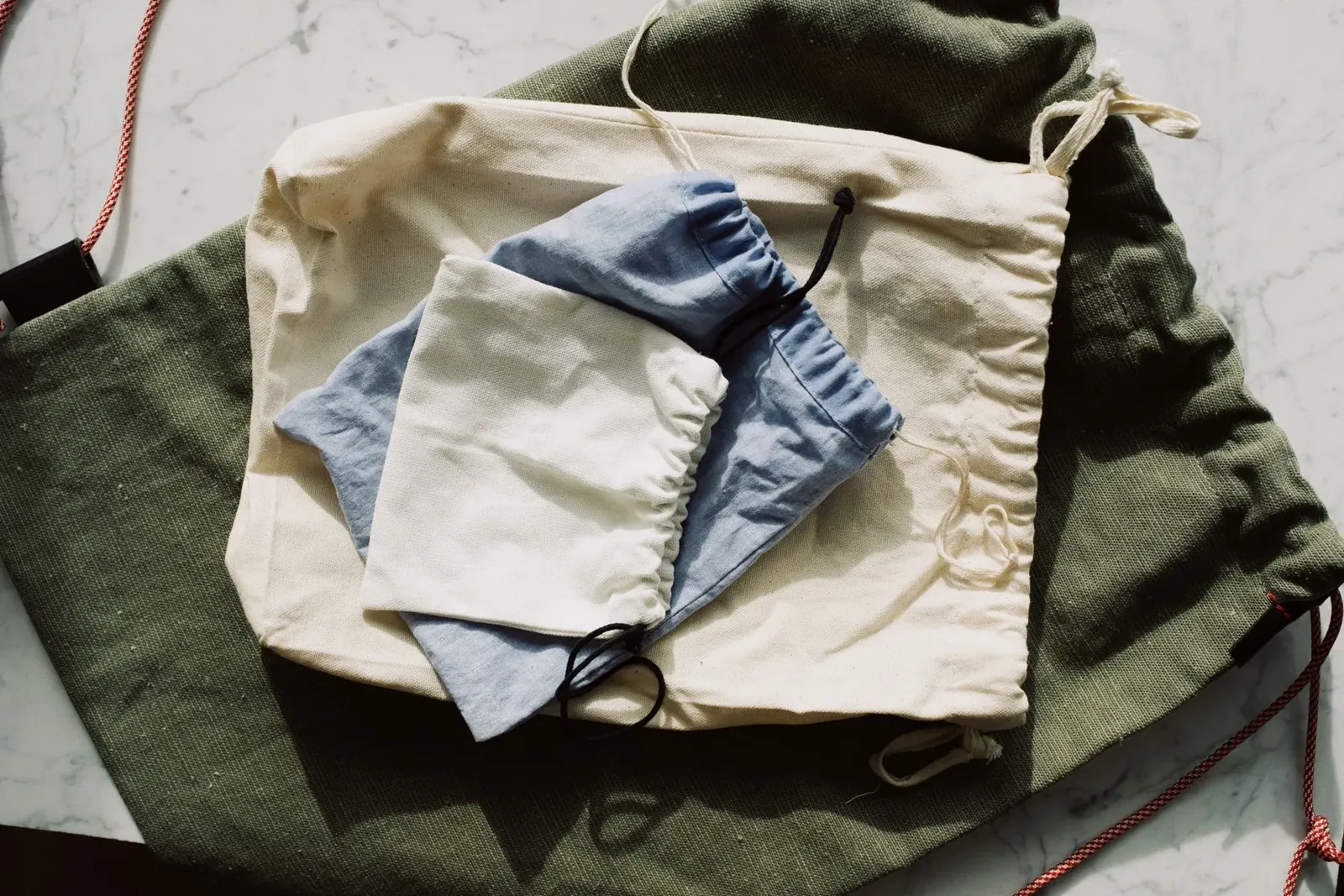 Reusable textile drawstring pouches arranged on a marble surface